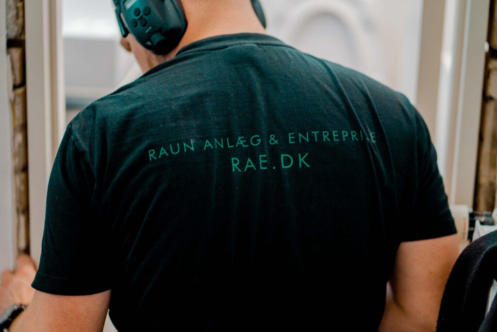 Håndværker der står med ryggen til, hvor der står "Raun Anlæg og entreprise"